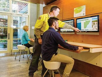 NPWS staff and visitors using the computers at Royal National Park Visitor Centre Royal National